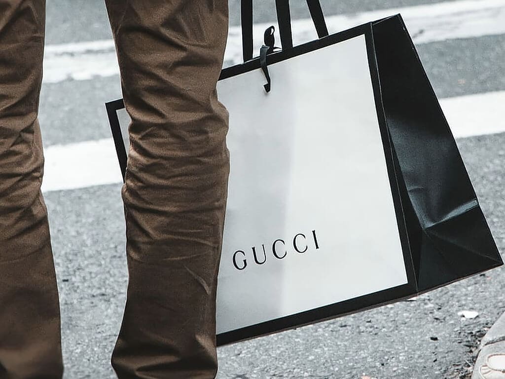 Homem segurando uma sacola da Gucci.